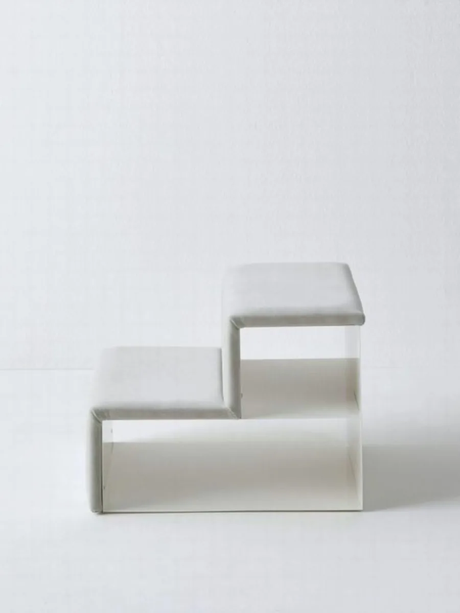 A two-tier upholstered pet step in front of a low bench