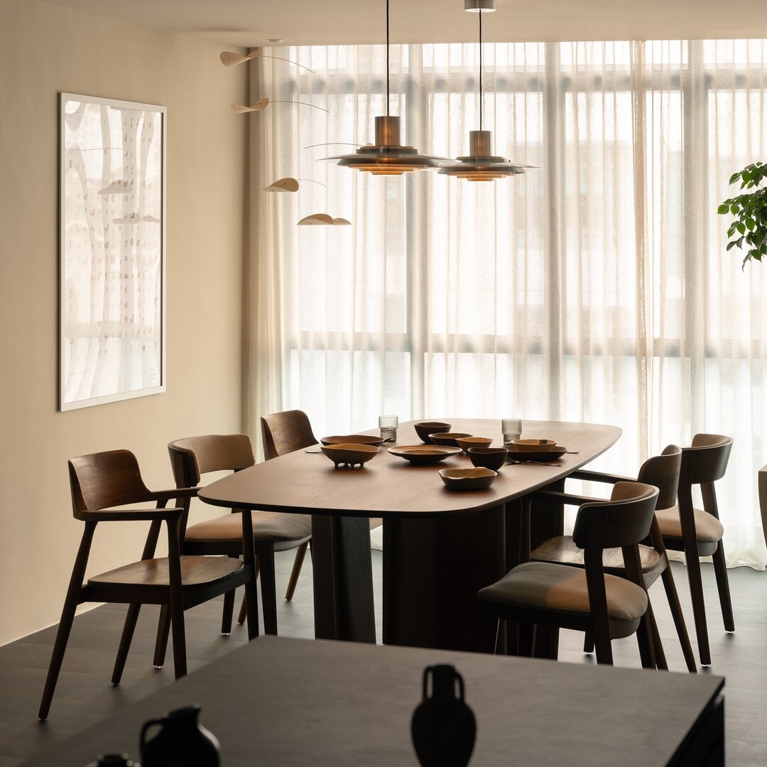 A dark walnut Son&Bear dining table under brass pendants in a customer's home